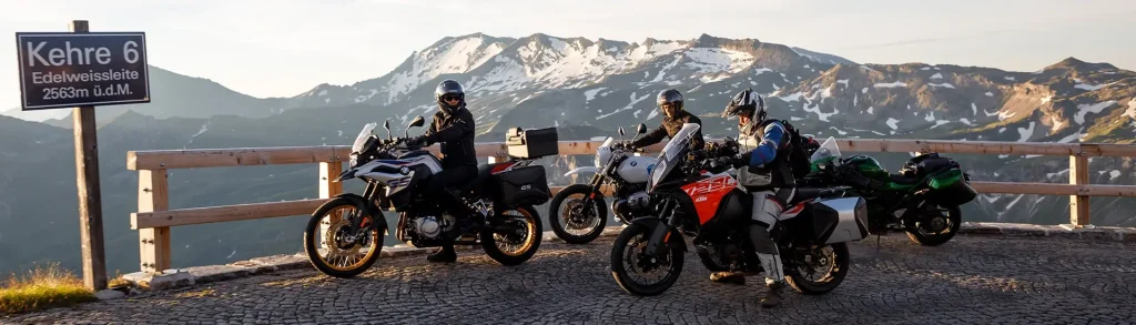 Motorradfahrer an der Kehre 6 der Edelweissstraße, Alpenpanorama im Hintergrund.